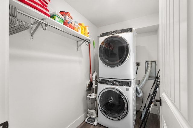 laundry area featuring stacked washer / drying machine, baseboards, and wood finished floors