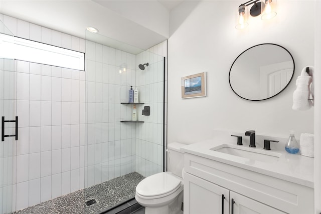 full bathroom with toilet, tiled shower, and vanity