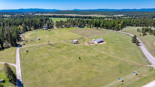 aerial view of property's location featuring mountains, rural landscape, and a forest