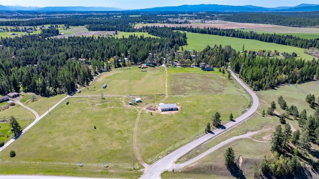 view of property location with a mountainous background, rural landscape, and a forest