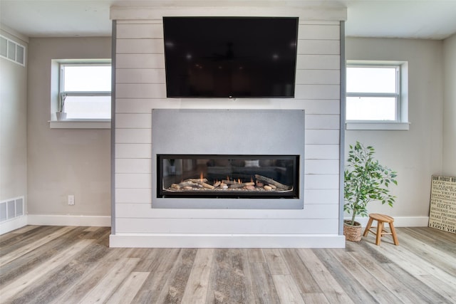 detailed view of a large fireplace, wood finished floors, and baseboards