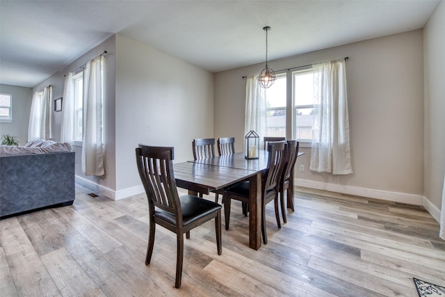 dining space featuring plenty of natural light, light wood-style floors, and baseboards