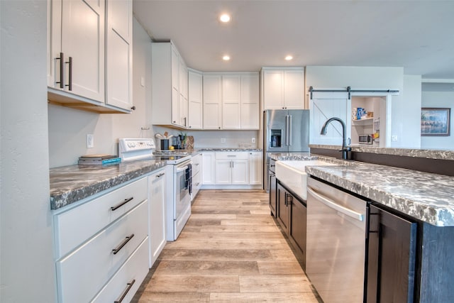 kitchen with electric stove, dishwasher, a sink, light wood-style flooring, and recessed lighting