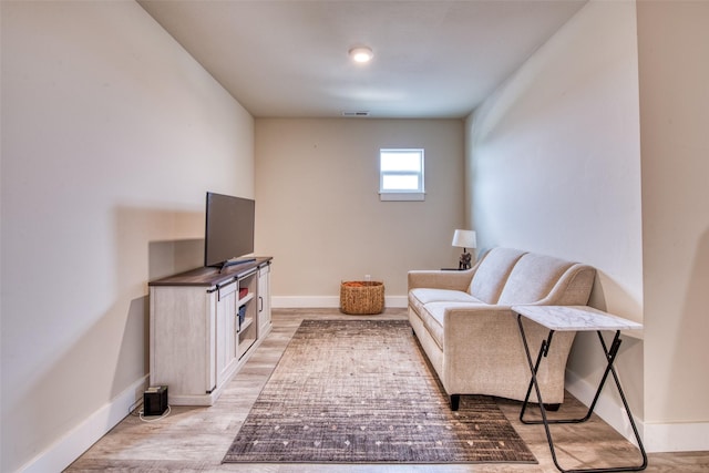 sitting room with baseboards and light wood-type flooring