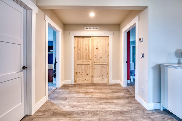 hallway with light wood finished floors, baseboards, and recessed lighting