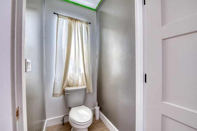 bathroom with baseboards, toilet, and wood finished floors
