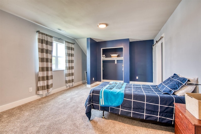 carpeted bedroom with baseboards and a barn door
