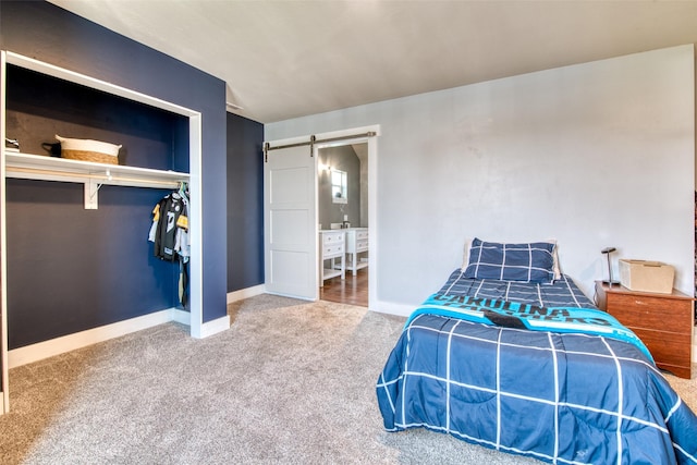 bedroom with carpet, a barn door, baseboards, and a closet