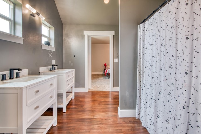 full bath featuring two vanities, wood finished floors, baseboards, and a shower with curtain