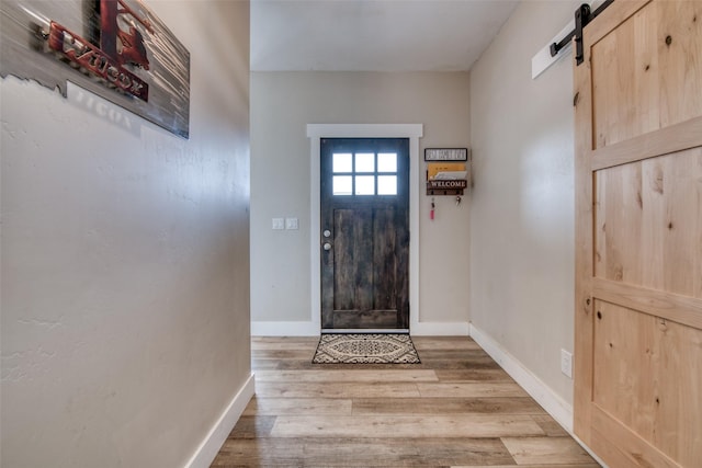 entryway featuring a barn door, wood finished floors, and baseboards