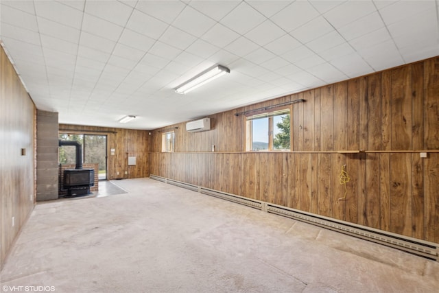 222 Lundeen Rd, Eureka, MT 59917 - below grade area with a wall unit AC, wooden walls, a wood stove, healthy amount of natural light, and a baseboard radiator