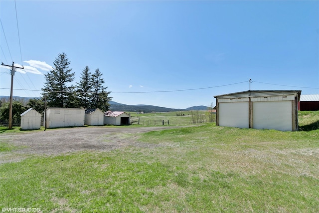 222 Lundeen Rd, Eureka, MT 59917 - view of green lawn with an outbuilding, a storage unit, a mountain view, and a garage