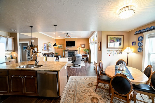 121 Choteau Ave NE, Great Falls, MT 59404 - kitchen featuring a sink, stainless steel dishwasher, a fireplace, a ceiling fan, and dark wood-style flooring