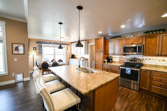 121 Choteau Ave NE, Great Falls, MT 59404 - kitchen with stainless steel appliances, a sink, brown cabinetry, dark wood-type flooring, and crown molding