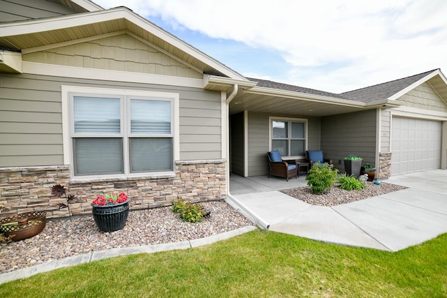 121 Choteau Ave NE, Great Falls, MT 59404 - view of exterior entry with an attached garage, stone siding, driveway, and roof with shingles