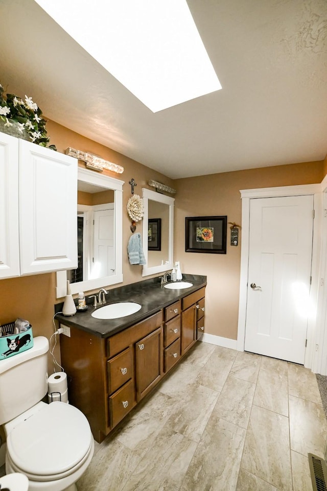 121 Choteau Ave NE, Great Falls, MT 59404 - bathroom featuring toilet, double vanity, a skylight, and baseboards