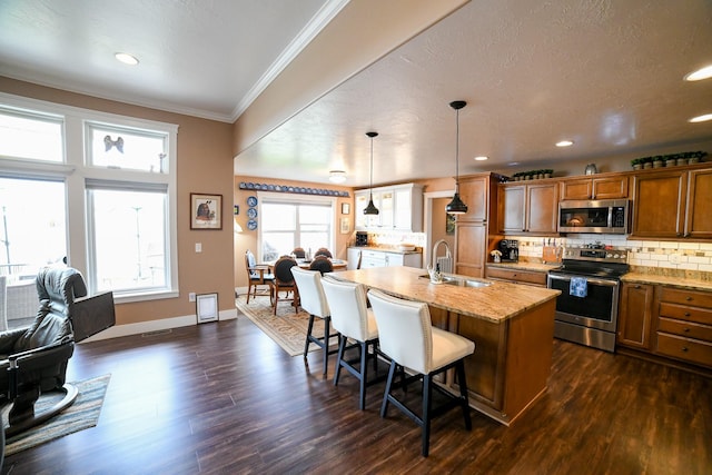 121 Choteau Ave NE, Great Falls, MT 59404 - kitchen featuring stainless steel appliances, a sink, brown cabinets, a breakfast bar, and crown molding