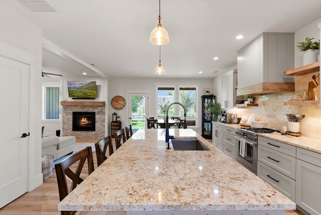5519 Golf Dr, Lolo, MT 59847 - kitchen with stainless steel range, a sink, tasteful backsplash, decorative light fixtures, and a center island with sink