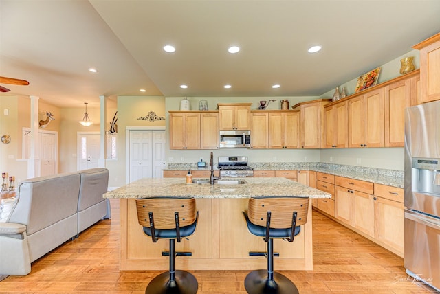 7175 Bootlegger Dr, Helena, MT 59602 - kitchen featuring appliances with stainless steel finishes, light brown cabinets, light wood-style flooring, a sink, and an island with sink
