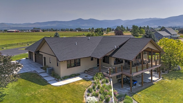 470 Salmon Way, Corvallis, MT 59828 - back of property with roof with shingles, a deck with mountain view, a lawn, and stucco siding