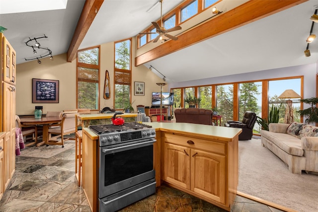 kitchen with gas stove, open floor plan, stone tile floors, beamed ceiling, and high vaulted ceiling