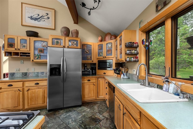 kitchen featuring appliances with stainless steel finishes, lofted ceiling, a sink, dark stone finish flooring, and light countertops