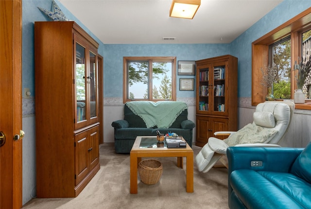 living area featuring light carpet, a wainscoted wall, and wallpapered walls
