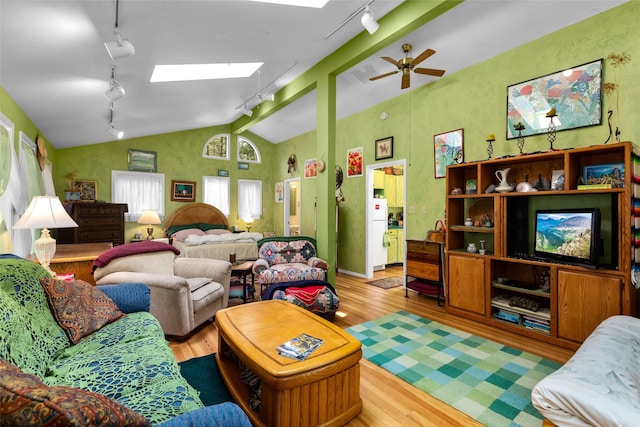 living room with rail lighting, lofted ceiling, light wood finished floors, a skylight, and a ceiling fan
