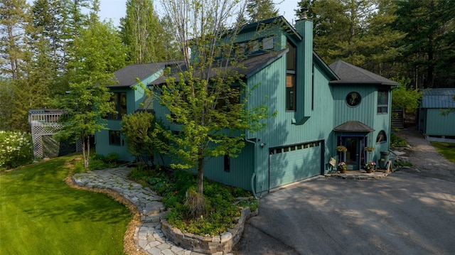 view of property exterior featuring asphalt driveway, a chimney, a garage, and a shingled roof