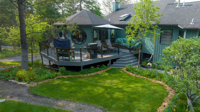 back of property featuring a shingled roof, a yard, a deck, and a chimney