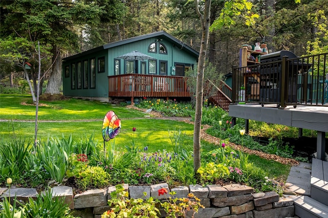 rear view of property featuring a deck, a yard, and stairs
