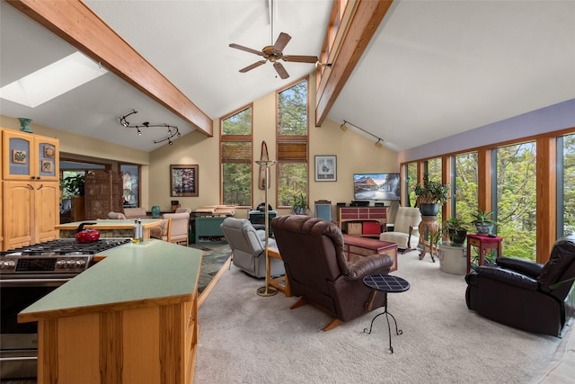 living area with beamed ceiling, high vaulted ceiling, a skylight, and a ceiling fan