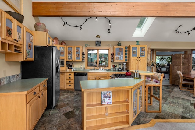 kitchen featuring stainless steel appliances, open shelves, a skylight, and dark stone finish flooring