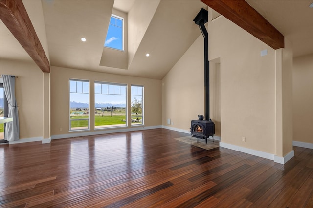 125 Schlegel View Rd, Kalispell, MT 59901 - unfurnished living room with a wood stove, wood finished floors, beamed ceiling, baseboards, and high vaulted ceiling
