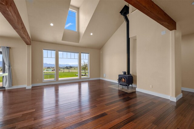 125 Schlegel View Rd, Kalispell, MT 59901 - unfurnished living room with a wood stove, wood finished floors, beam ceiling, and high vaulted ceiling
