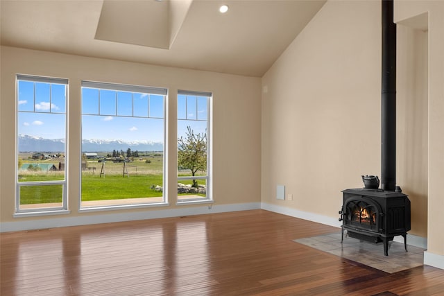 125 Schlegel View Rd, Kalispell, MT 59901 - unfurnished living room featuring wood finished floors, a wood stove, baseboards, a mountain view, and vaulted ceiling