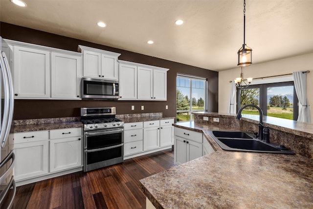 125 Schlegel View Rd, Kalispell, MT 59901 - kitchen with appliances with stainless steel finishes, dark wood-style floors, white cabinetry, hanging light fixtures, and recessed lighting