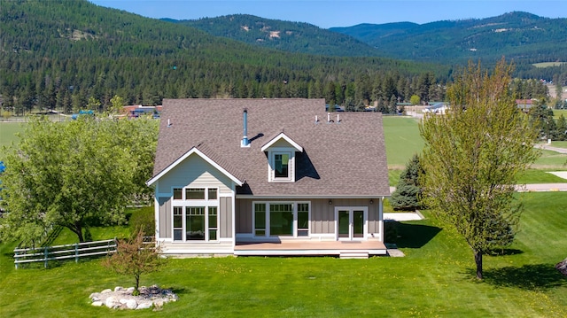 125 Schlegel View Rd, Kalispell, MT 59901 - rear view of house with a wooded view, roof with shingles, a deck with mountain view, and board and batten siding