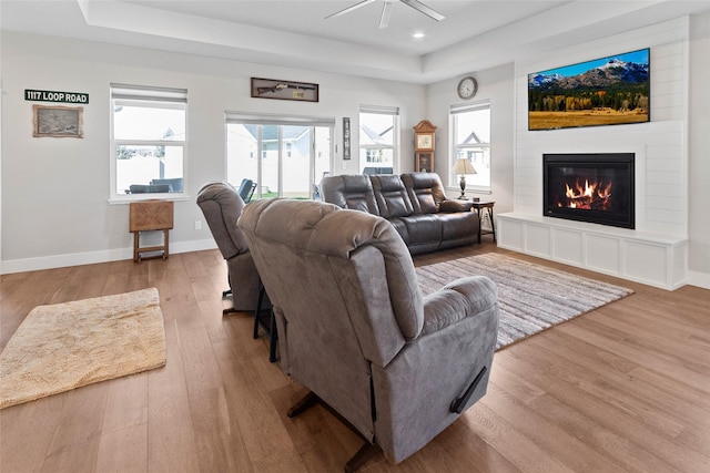131 Owl Loop, Kalispell, MT 59901 - living area featuring a raised ceiling, wood finished floors, a large fireplace, healthy amount of natural light, and recessed lighting