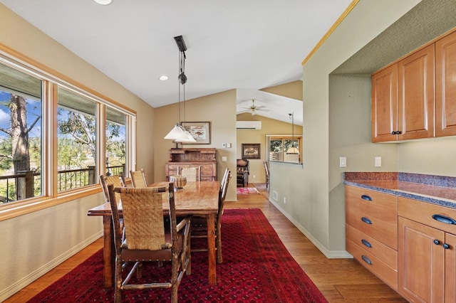 dining space with plenty of natural light, light wood-style floors, an AC wall unit, lofted ceiling, and baseboards