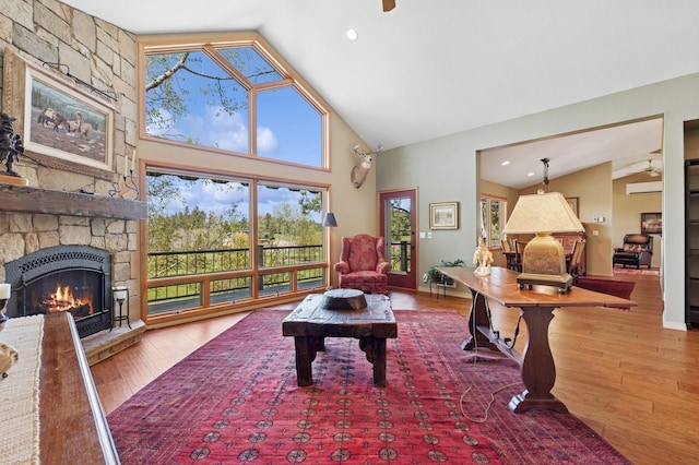 living room featuring hardwood / wood-style flooring, high vaulted ceiling, a fireplace, and ceiling fan