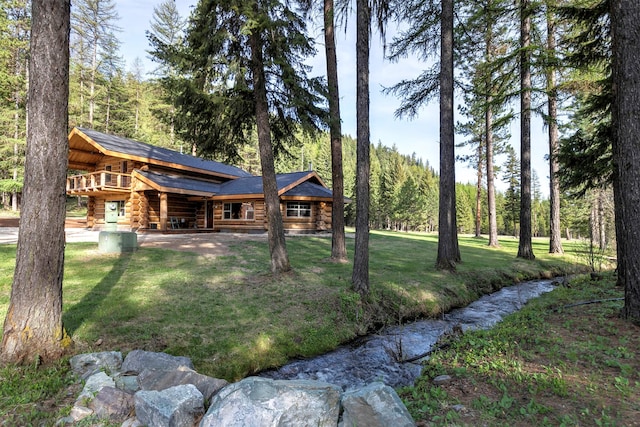 view of green lawn with a forest view