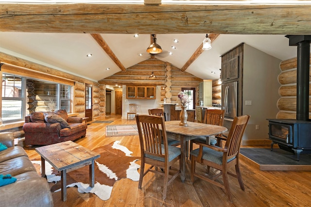 dining room featuring rustic walls, a wood stove, plenty of natural light, light wood-style flooring, and recessed lighting