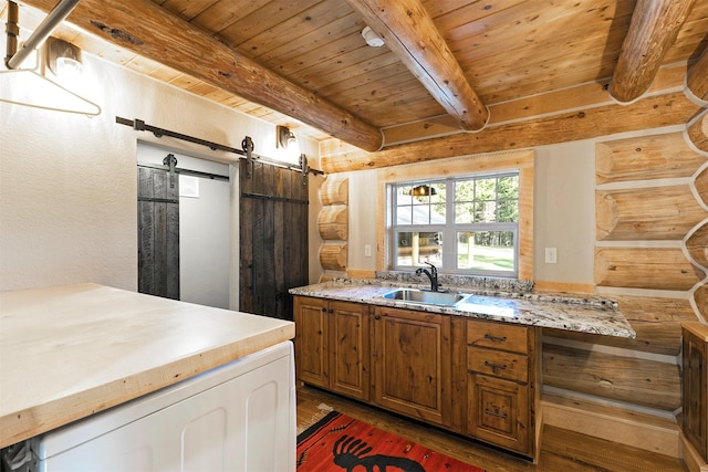 4991 Petty Creek Rd, Alberton, MT 59820 - kitchen featuring log walls, a wooden ceiling with exposed beams, wood finished floors, brown cabinetry, and a barn door