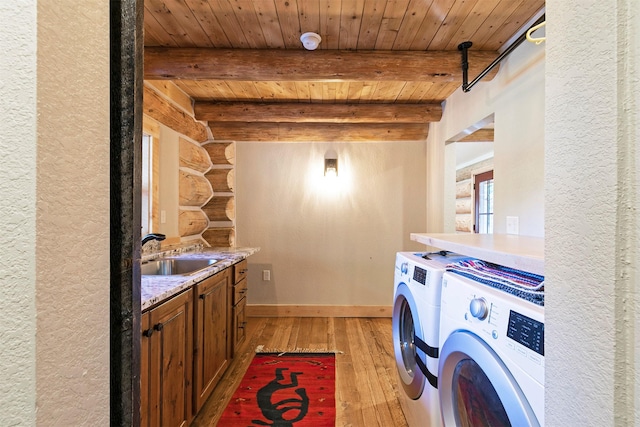 4991 Petty Creek Rd, Alberton, MT 59820 - laundry area featuring light wood-style floors, log walls, washing machine and clothes dryer, wooden ceiling, and a textured wall