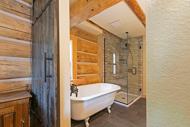bathroom with a shower stall, a textured wall, a freestanding bath, and a sink