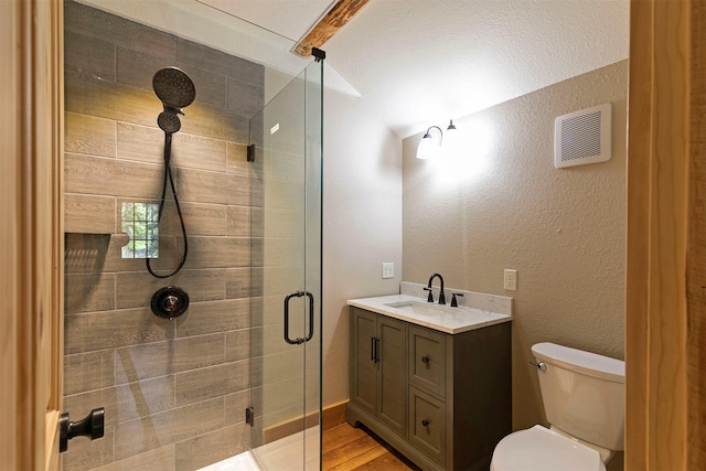 full bath with a shower stall, toilet, wood finished floors, vanity, and vaulted ceiling