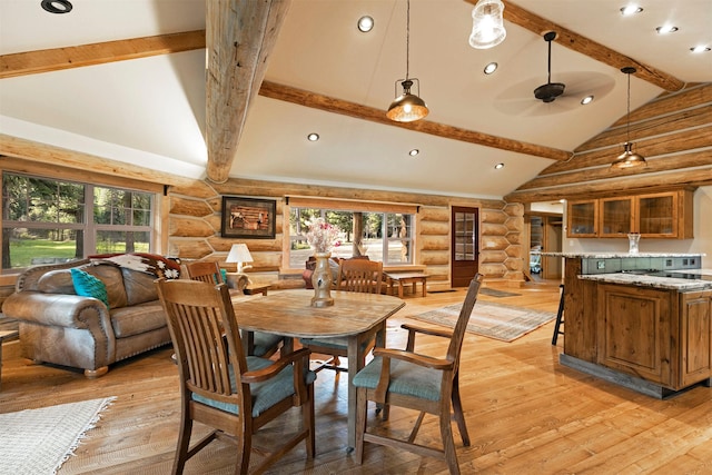 dining room with log walls, healthy amount of natural light, light wood finished floors, beam ceiling, and high vaulted ceiling