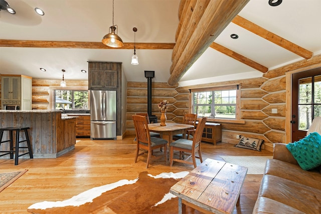 dining room with rustic walls, a wood stove, healthy amount of natural light, light wood-style floors, and recessed lighting
