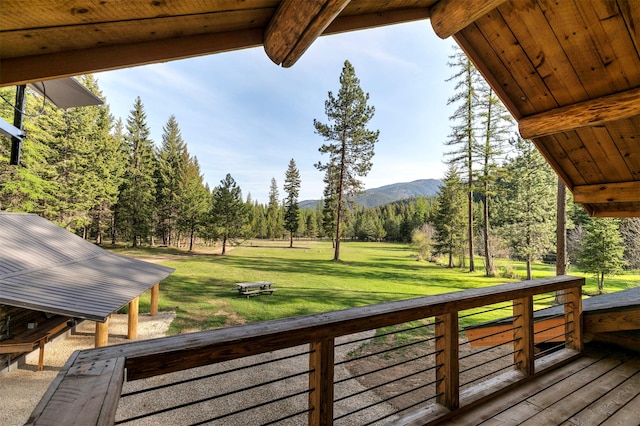 wooden deck with a mountain view and a lawn
